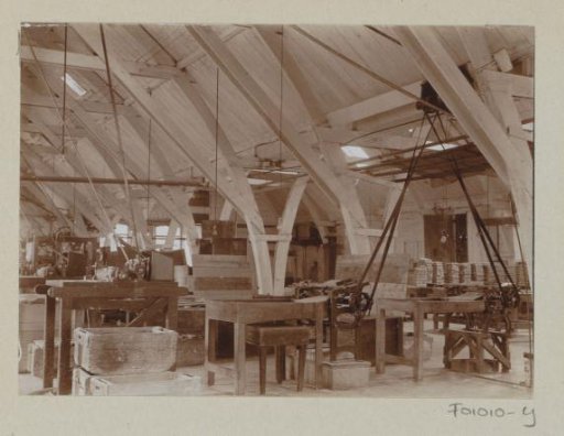 Interior of a factory hall with workbenches and drive belts for machines