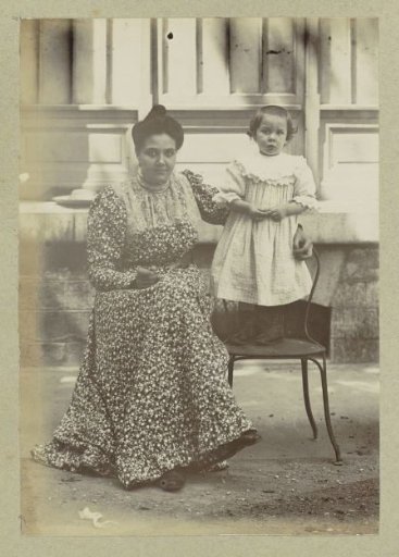 Portrait of a seated woman with a child standing on a chair