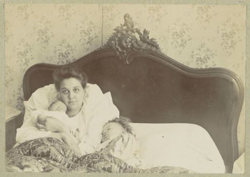 Mother with a baby and a child in a lying-in bed