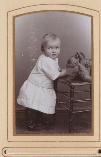 Portrait of a child leaning on a chair with toys