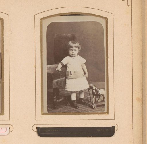 Portrait of a girl, standing by a chair with a hobby horse