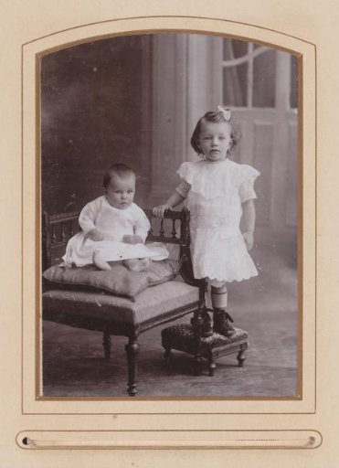 Portrait of a sitting baby and a standing girl