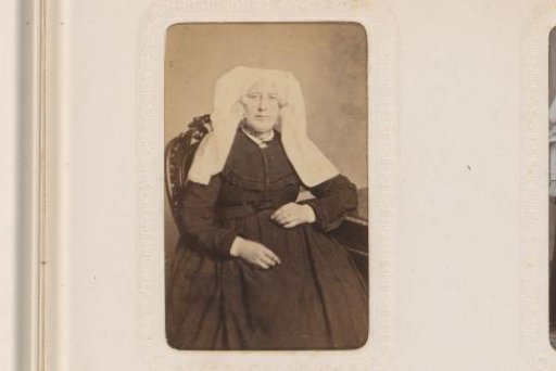 Portrait of a seated woman in a white cap and ear-covers