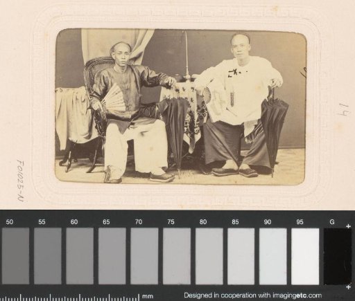 Portrait of two sitting Chinese men with umbrellas