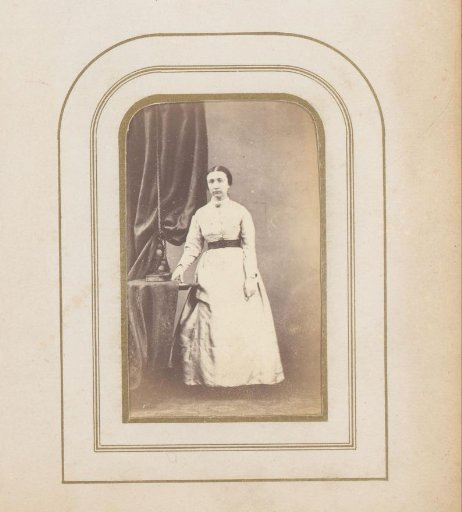 Portrait of a woman standing at a table with a photo album