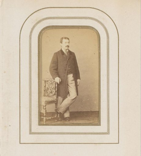 Portrait of a man with a mustache, standing by a chair