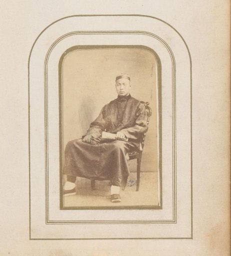 Portrait of a seated man with a hat and gloves