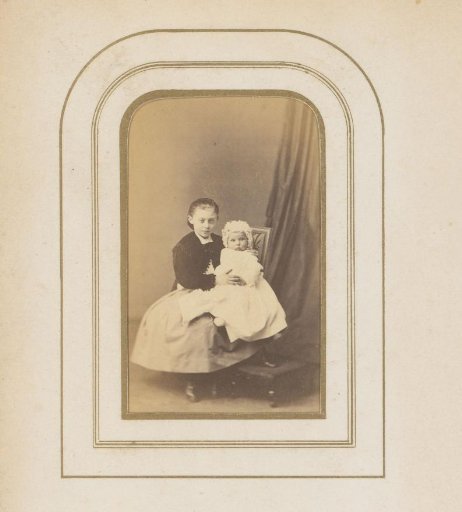 Portrait of a girl, seated on a chair with a baby on her lap