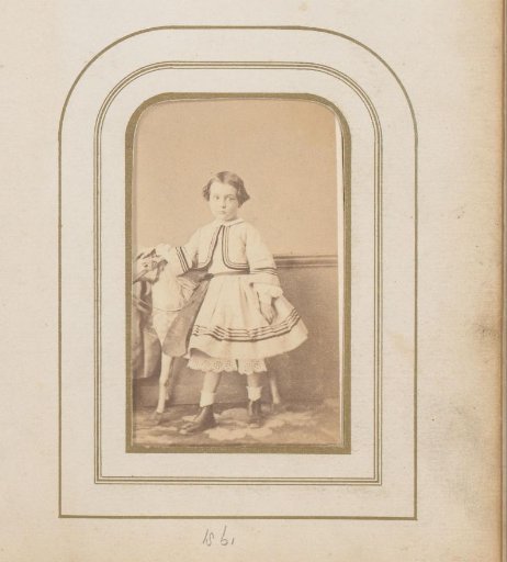 Portrait of a girl standing by a toy horse