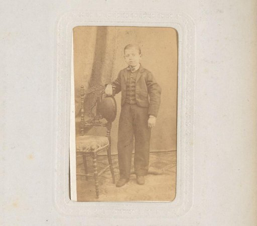 Portrait of a Boy Standing by a Chair with a Hat