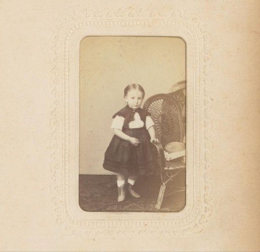 Portrait of a girl standing by a chair with a hat