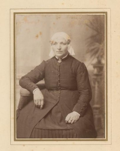 Portrait of a seated woman in a white cap and ear-covers