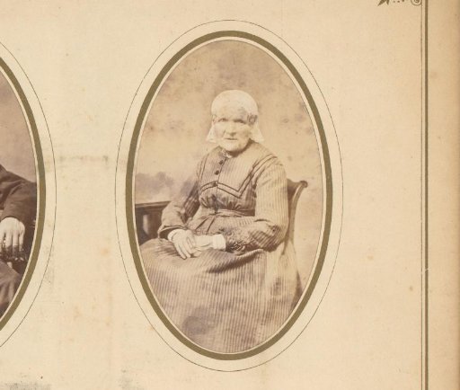 Portrait of an elderly seated woman in a white cap and ear-covers