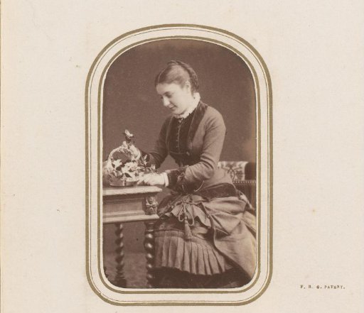 Portrait of a woman seated at a table with a basket of flowers