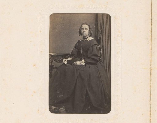 Portrait of a woman with a book on her lap, seated at a table
