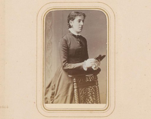 Portrait of a standing woman, leaning on the arm of a prayer stool