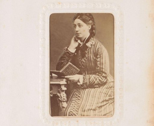 Portrait of a woman holding an open book, seated at a table