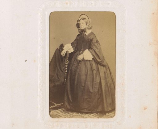 Portrait of a Woman in a Black Dress with a Hat, Standing by a Chair