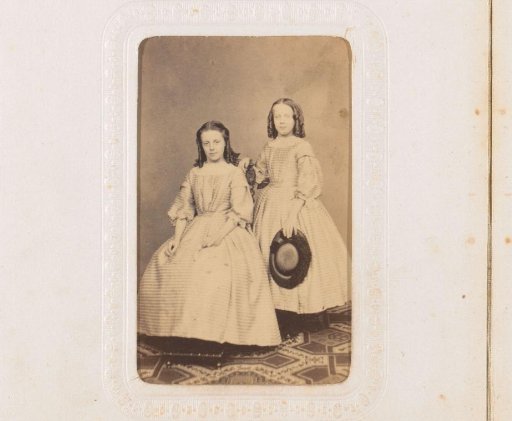 Portrait of a seated girl and a standing girl with a hat in her hand