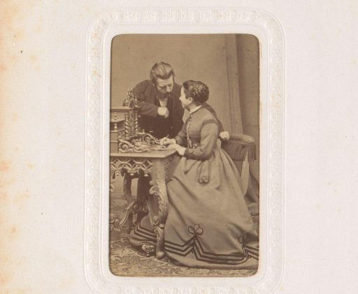 Portrait of a man and a woman, the woman seated at a table with a pen in her hand