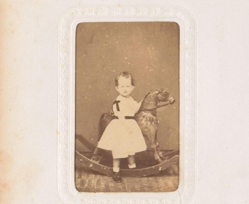 Portrait of a girl in a white dress, standing by a rocking horse