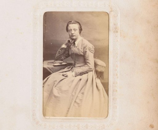 Portrait of a young woman, seated at a table on which two books lie