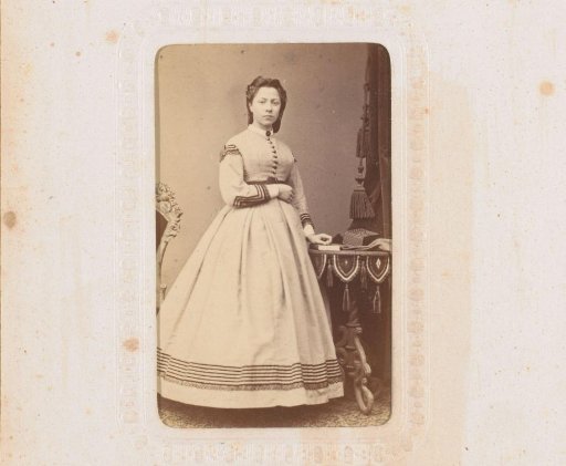 Portrait of a young woman standing by a table with a book