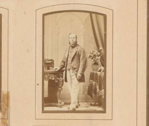 Portrait of a man with a ring beard, standing by a table
