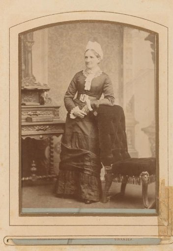Portrait of a Standing Woman with a White Cap by a Chair, Identified as M.H. Wiglesworth