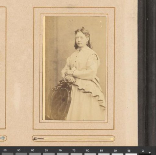 Portrait of a young woman standing by a chair