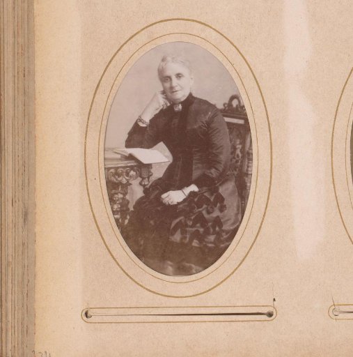 Portrait of a woman, seated at a table with a book