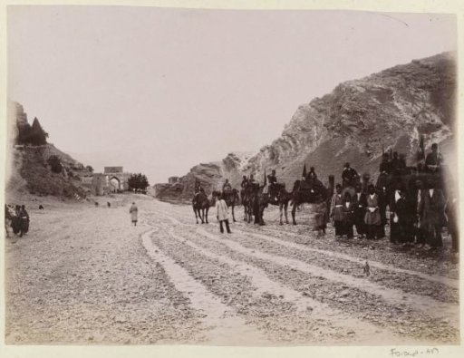 Cavalry party leaves Shiraz, with the Quran Gate in the background