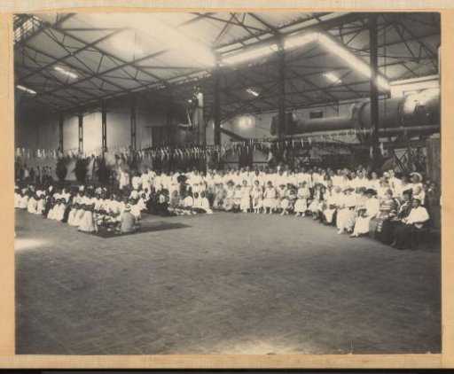 Group portrait of Indonesians and Europeans at a festive occasion in a factory hall in the Dutch East Indies