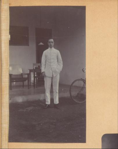 Man in tropical clothing standing in front of a house in the Dutch East Indies
