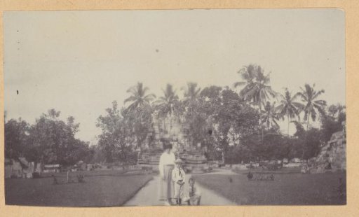 Woman with two children at an ancient building, possibly the Borobudur on Java