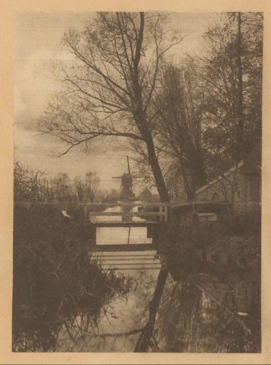 View of houses along a canal with a windmill at the end in the Netherlands