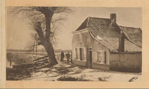 Men by a snow-covered farmhouse with a thick tree in front in the Netherlands