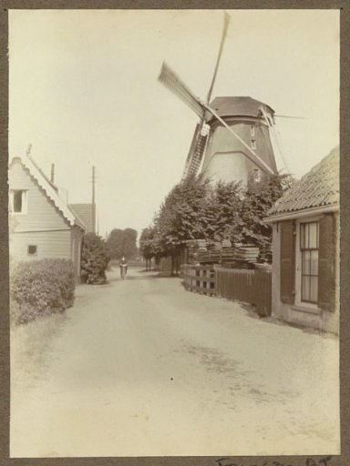 Village street with cyclist and windmill near Weesp