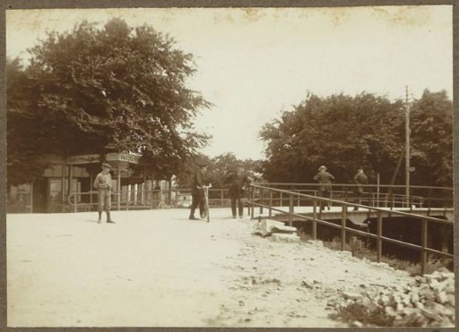 Passers-by at the Hartveldse bridge in Diemen, with advertising signs for Amstelbier in the background