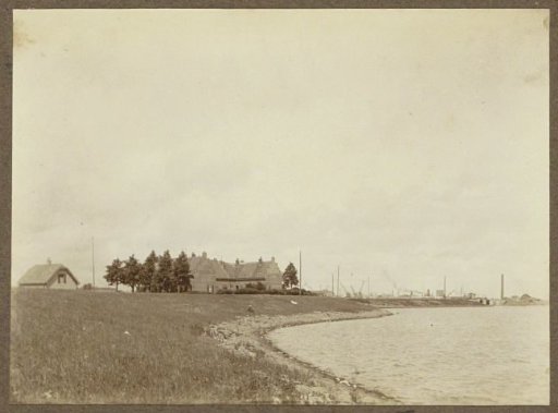 Houses on a dyke near Zeeburg, on the horizon excavators