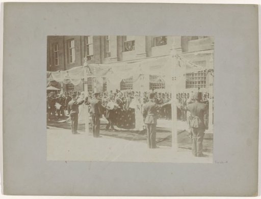 Wilhelmina walking under a canopy in front of the Royal Palace, on the way to the inauguration in the Nieuwe Kerk
