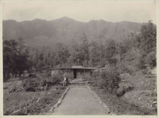 Man sitting in front of a hut in the Dutch East Indies