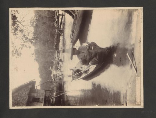 Woman nursing a child in a boat, possibly in Surabaya