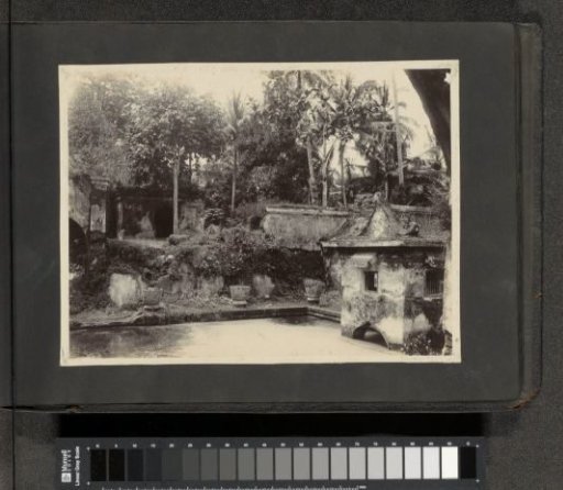 Dilapidated buildings by a pond in the Dutch East Indies