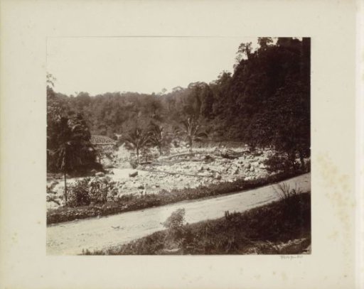 Dried-up riverbed with a railway bridge over a stream in the Dutch East Indies