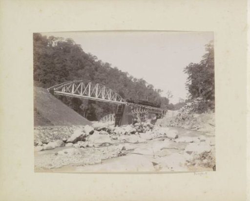 Railway bridge over a stream with a passing train in the Dutch East Indies