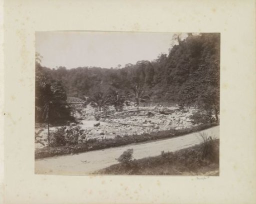 Dried-up riverbed with a railway bridge over a stream in the Dutch East Indies