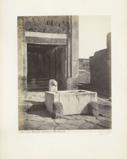 Remains of buildings in Pompeii with a fountain with a statue of Fortuna in the foreground