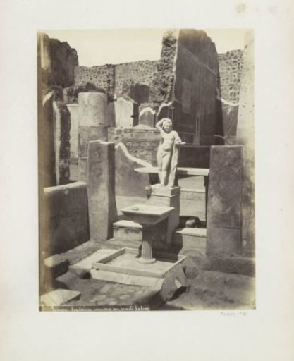Remains of a house in Pompeii with a statue and a basin