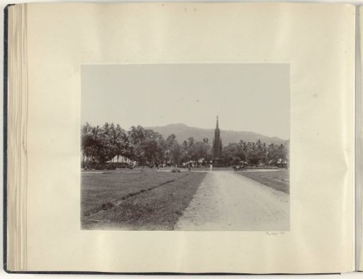 Monument on a square in the Dutch East Indies with a carriage and a velocipede in front